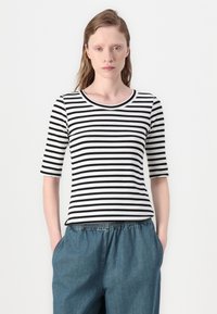 Schwarz-weiß gestreiftes T-Shirt mit Rundhalsausschnitt und Dreiviertelärmeln, kombiniert mit blauen Pants mit elastischem Bund.