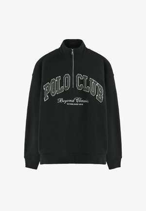 Felpa nera con colletto alto e zip a metà. Presenta "POLO CLUB" ricamato in grassetto in bianco e grigio, con "Beyond Classics" sottostante.