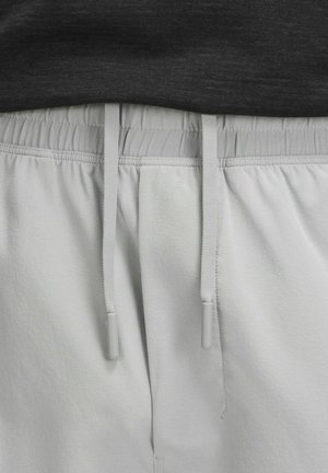 Pantaloni jogger grigio chiaro con vita elasticizzata e coulisse. Tessuto morbido con una finitura liscia e dettagli con tasche laterali visibili.