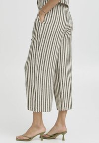 Pantalons cropped rayés en mélange de lin, présentant des rayures verticales noires et blanches, des poches latérales et une coupe décontractée.