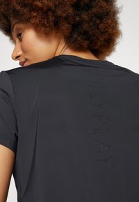 Black athletic t-shirt with short sleeves, featuring a smooth texture and "ONLY PLAY" perforated detail on the back.
