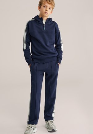 Navy blue tracksuit with a half-zip hoodie and matching pants, featuring white side stripes and ribbed cuffs. Textured fabric, sporty design.