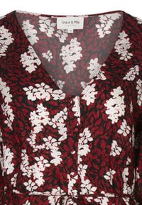 Bloemjurk van Grace & Mila, met een diepe V-hals, bordeauxkleurige stof met witte bloemenpatronen en een geplooide taille.