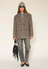 Manteau croisé en pied-de-poule marron, pull gris, chemise rayée bleue, jean gris, sac noir à franges, ballerines noires, bonnet gris, lunettes de soleil.