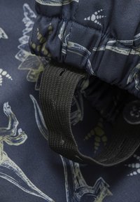 Marineblått tyg med abstrakta mönster av fladdermöss och löv. Har en elastisk kant och ett mörkt texturerat band med en ringad design.