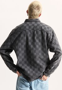 Grijze geruite flanellen shirt met knoopsluiting bij de manchetten, kraag en een gemêleerd patroon. Heeft een relaxte pasvorm en een licht gebogen zoom.