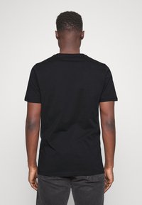 Svart kortärmad T-shirt med rund halsringning, tillverkad av mjuk bomull. Bakifrån visas en slät yta och en enkel design utan synliga logotyper.