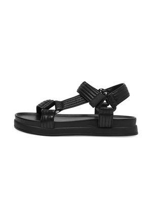 Czarna sandałka na otwartym palcu z wyściełanymi, regulowanymi paskami na stopie i wokół kostki oraz płaską, lekko podniesioną podeszwą.