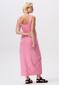 Roze mouwloze maxi-jurk met een ronde halslijn, een strakke taille en een vloeiende rok. Het heeft een gladde textuur en een effen kleur ontwerp.