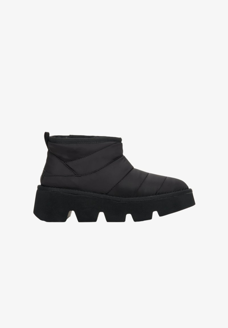 Černé kotníkové boty s prošívaným textilním svrškem, silnou černou gumovou podrážkou a poutkem na zadní straně; mají robustní textured design.
