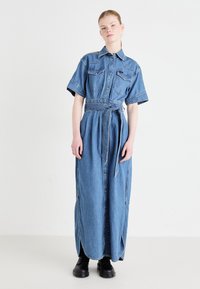 Gaišzila džinsa maksi krekls-vakardrēbē, īsām piedurknēm, ar pogām priekšpusē, jostu vidukļa rajonā un divām krūšu kabatām. Gluda tekstūra.