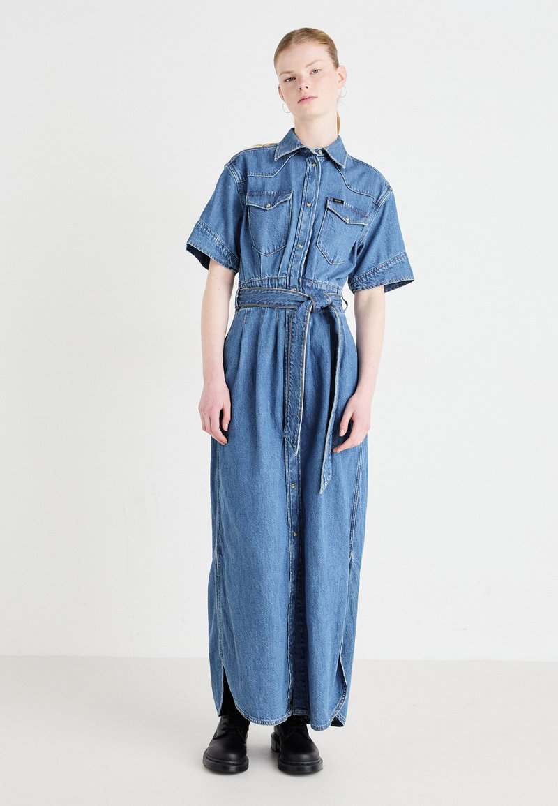 Gaišzila džinsa maksi krekls-vakardrēbē, īsām piedurknēm, ar pogām priekšpusē, jostu vidukļa rajonā un divām krūšu kabatām. Gluda tekstūra.