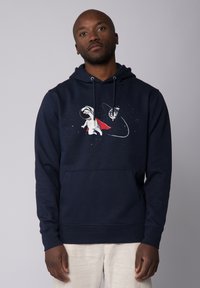 Sweat à capuche bleu marine avec une poche frontale, présentant un graphique de chien astronaute en blanc et rouge, avec des éléments spatiaux en arrière-plan.