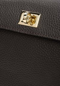 Donkerbruin leren handtas met een goudkleurige rechthoekige sluiting en contrasterende stiksels langs de rand. Compact ontwerp met een gladde afwerking.