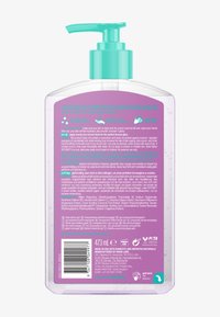 Bouteille transparente avec étiquette violette et distributeur à pompe turquoise contenant un gel autobronzant, incluant des instructions d'utilisation, des avertissements et une certification végan.