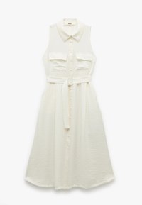 Vestido blanco sin mangas con cuello, dos bolsillos frontales, cintura ceñida con un cinturón y diseño de botones. Fabricado en tejido texturizado.