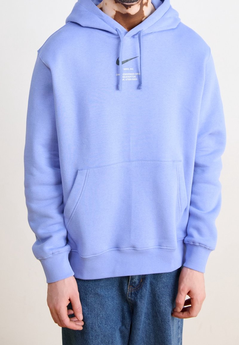 Light purple hoodie made from soft material, featuring a kangaroo pocket and a black Nike logo printed on the chest. Long sleeves with ribbed cuffs.