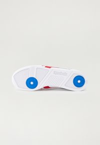 Baltos sportinės avalynės padas su mėlynomis akcentais, tekstūruota sukibimo grosa ir išpjaustytu Reebok logotipu šone. Apvalus mėlynas detalė kulne.