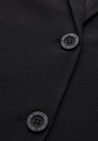 Blazer nero in tessuto con bottoni a camicia, caratterizzato da due bottoni rotondi neri con incisione "CECIL", texture liscia e vestibilità tailored.