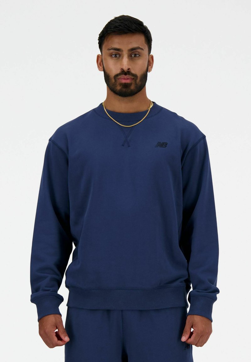 Sudadera azul marino de tela suave con mangas largas, puños y dobladillo acanalados, que presenta un pequeño logo negro en el pecho.