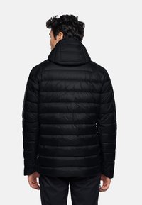 Giacca nera imbottita con colletto alto e cappuccio, caratterizzata da un design trapuntato e una texture liscia. La vista posteriore mostra polsini ed orlo elastici.