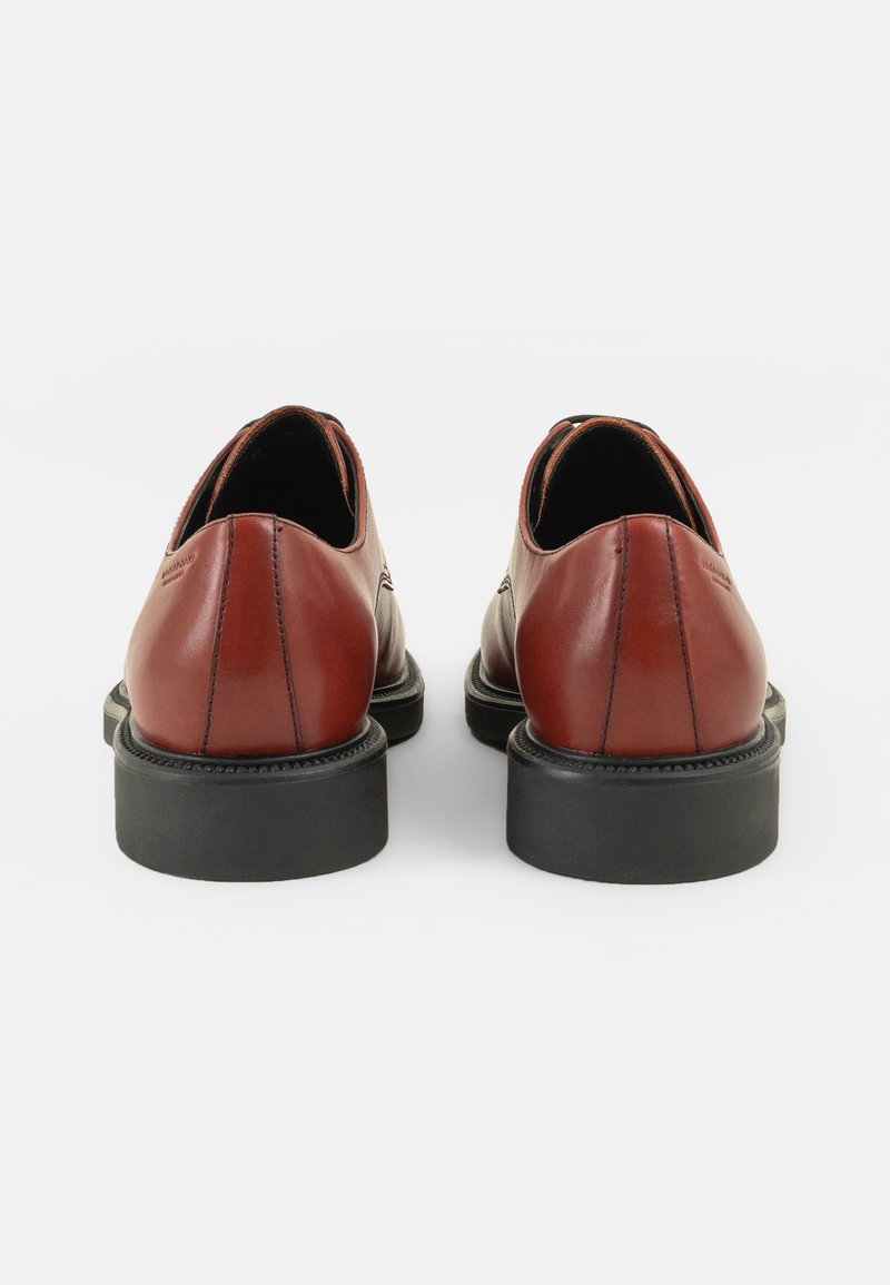 Brązowe skórzane buty o gładkim wykończeniu, okrągłym nosku i czarnej gumowej podeszwie. Cechują się kontrastowym przeszyciem i minimalistycznym designem.