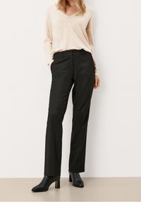 Schwarze, maßgeschneiderte Hose mit geradem Bein, kombiniert mit einer hellbeigen Bluse, die über drei dekorative Knöpfe am Ausschnitt verfügt.