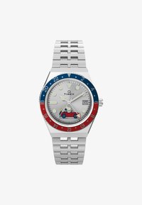 Reloj Timex con correa de acero, esfera plateada, bisel azul y rojo, presenta a Snoopy en un coche rojo y tiene una ventanilla de fecha a las 3 en punto.