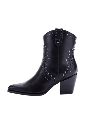 Botas de tobillo de cuero negro con punta afilada, acentos de tachuelas y un tacón bloque de altura media. Presentan una lengüeta para ponerse y quitarse fácilmente.