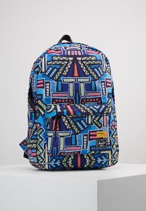 Plecak z przednią kieszenią na zamek, niebieska podstawa i kolorowy geometryczny wzór plemienny w zielonym, różowym i granatowym, prezentowany na białym postumencie.