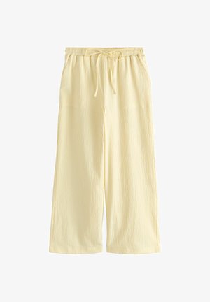 Dzelteni platās bikses, izgatavotas no teksturēta auduma, ar elastīgu jostasvietu un saiti, kā arī sānu kabatām.