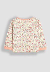 Haut à manches longues fleuri en tissu doux ; présente un fond rose pâle avec de petites fleurs multicolores et des poignets et un col couleur pêche.