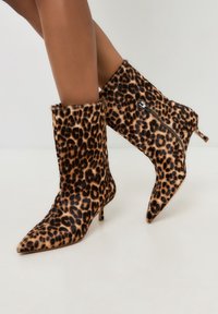Leopardprint enkellaarsjes met spitse neuzen, van textuurvol nepleer, en een zijrits accent. Voorzien van een slanke hak en een met bont afgewerkt bovenste deel.