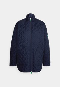 Chaqueta acolchada de color azul marino con cremallera frontal, cuello alto, dos bolsillos frontales y un pequeño parche de logo en la manga izquierda.