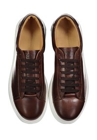 Sneakers in pelle marrone con una texture liscia, lacci marrone scuro e suole in gomma bianche. Presentano un logo impressa sul lato.