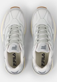 Białe siateczkowe i szare zamszowe sneakersy z jasnoszarymi akcentami, okrągłym noskiem i teksturowaną podeszwą. Posiadają przeszywane linie i logo na języku.