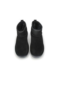 Botines negros de ante con un suave forro de forro polar, puntera redondeada, costuras sutiles y una pestaña trasera para facilitar el uso.