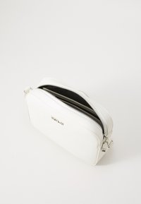 Witte nepderen pouch met twee ritssluitingen, een gladde textuur en zilverkleurige hardware. Minimalistisch ontwerp zonder zichtbare patronen.