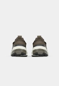 Braune Sportschuhe mit strukturiertem Obermaterial, schwarzen Akzenten und einer gepolsterten weißen Sohle. Mit Schlaufen an der Ferse für ein einfaches Anziehen.