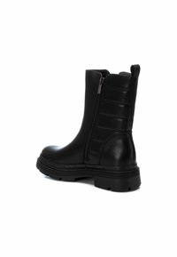 Stivali alla caviglia in pelle nera con una finitura liscia, dotati di una zip laterale, dettagli testurizzati e una suola robusta per una maggiore aderenza.