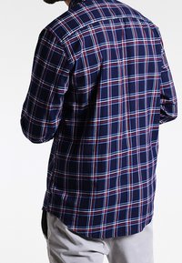 Camisa de cuadros azul marino con patrones de cuadrícula en rojo y blanco, cuello abotonado, mangas largas y dobladillo curvado en la parte inferior.