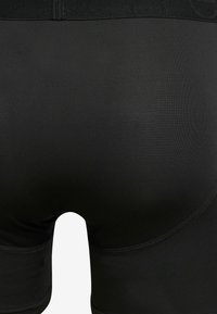 Shorts de sport ajustés noirs en matériau lisse et extensible, avec une large taille et des détails de couture discrets.