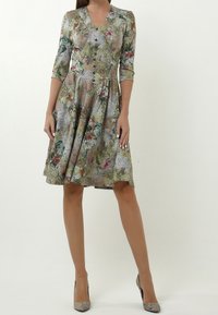 Blumengemusterte Kleid mit V-Ausschnitt, Dreiviertelärmeln und schwingendem Rock. Hergestellt aus leichtem Stoff in gedämpften Grün-, Rosa- und Blautönen.