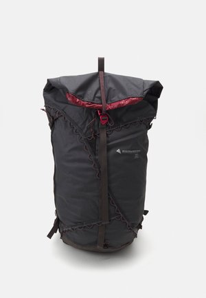 Mochila de tecido preto com fecho de cordão, forro interior vermelho, detalhe de borda em forma de onda e duas alças laterais para ajuste.