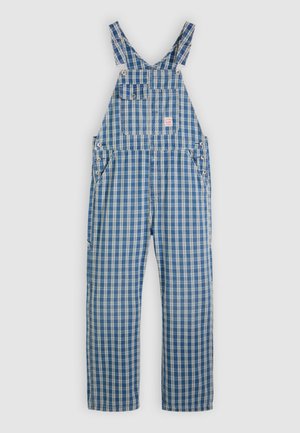 Mėlynos ir baltos languotos puskombinezonis su plačiomis petnešėlėmis, priekinė kišenė ir šoninės kišenės. Pagamintas iš tvirto audinio, su mygtukų detalėmis šonuose.