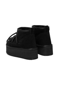 Bocanci negri din suede, până la gleznă, cu o talpă groasă din cauciuc, având șireturi și un design texturat pe spate.