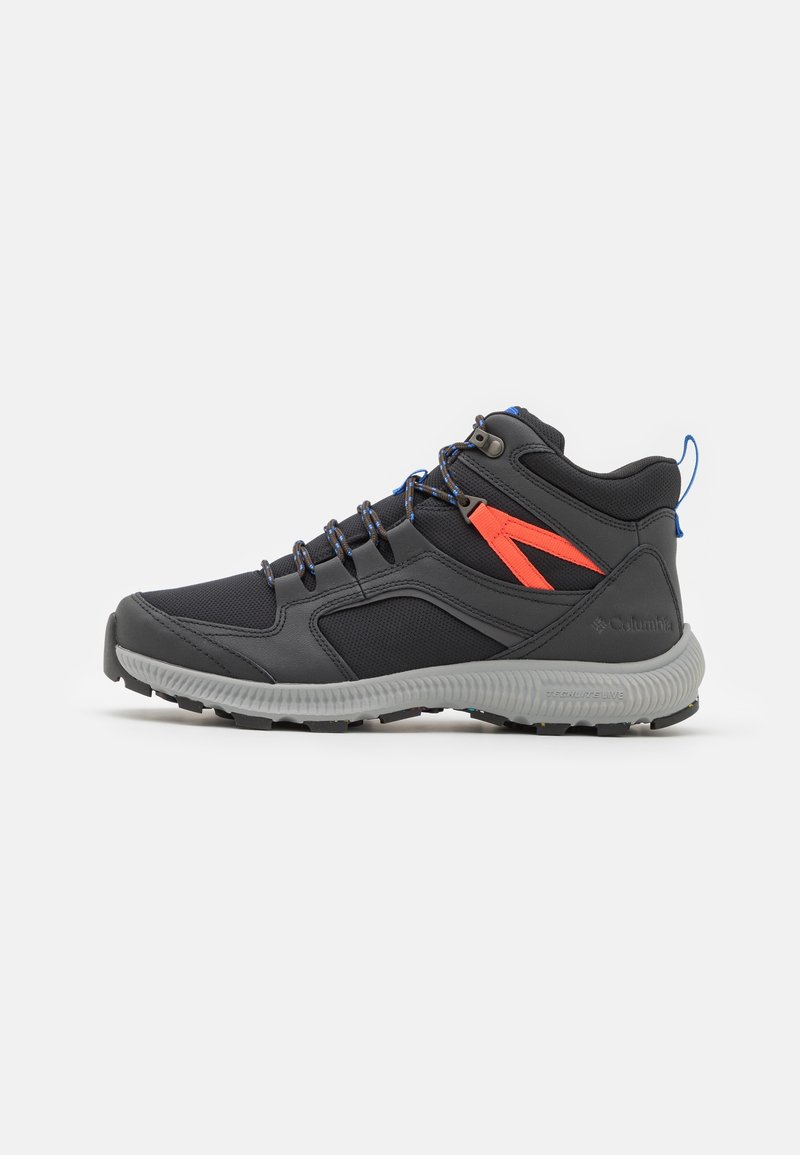 Chaussure de randonnée mi-haute noire et grise avec un détail orange sur le côté, des lacets bleu accentué et une semelle grise texturée sur fond blanc.