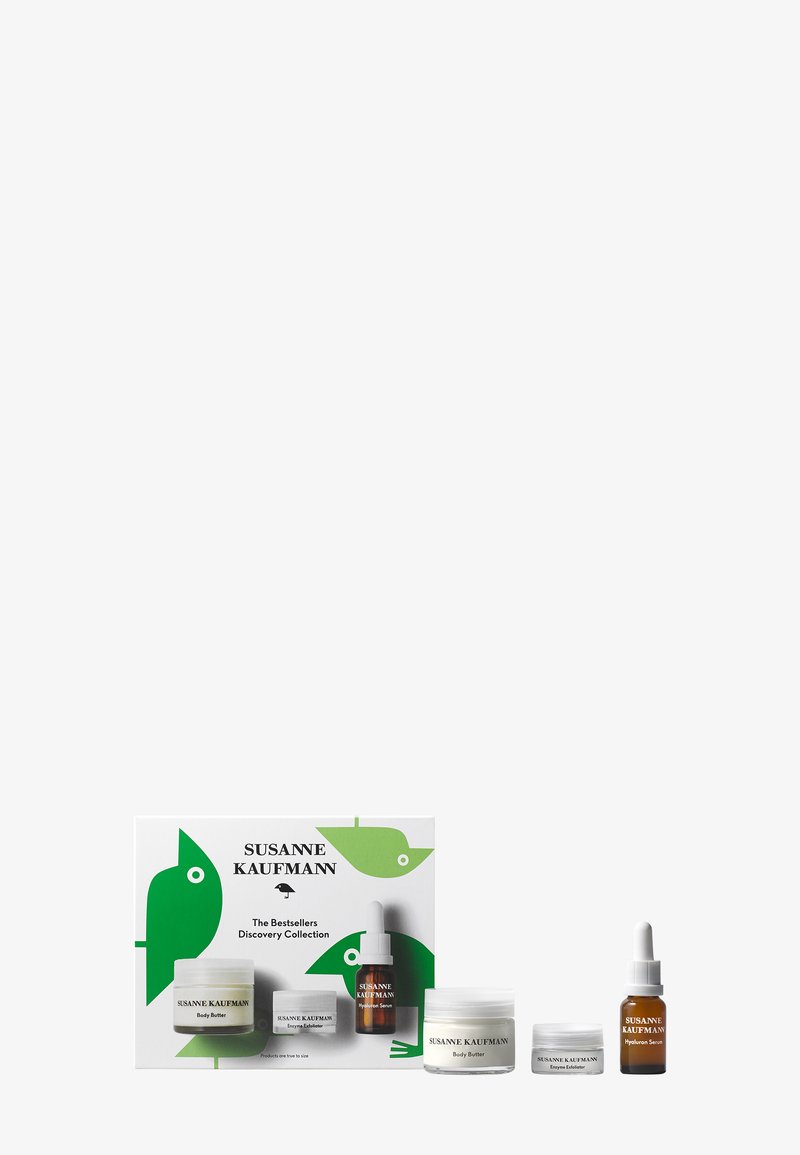 Ensemble de produits de soin de la peau dans une boîte au design vert et blanc. Comprend trois contenants : deux pots blancs et une bouteille compte-gouttes marron.