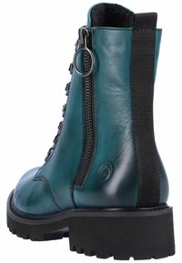 Botte de cheville en cuir teal avec des côtés élastiques noirs et des détails de fermeture éclair, surface texturée, semelle noire épaisse et logo embossé sur le côté.