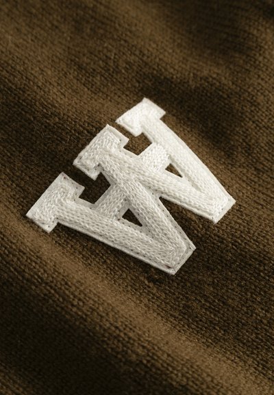 Tissu marron avec un tricot texturé, mettant en avant un logo "W" brodé en blanc, cousu avec des bords nets.